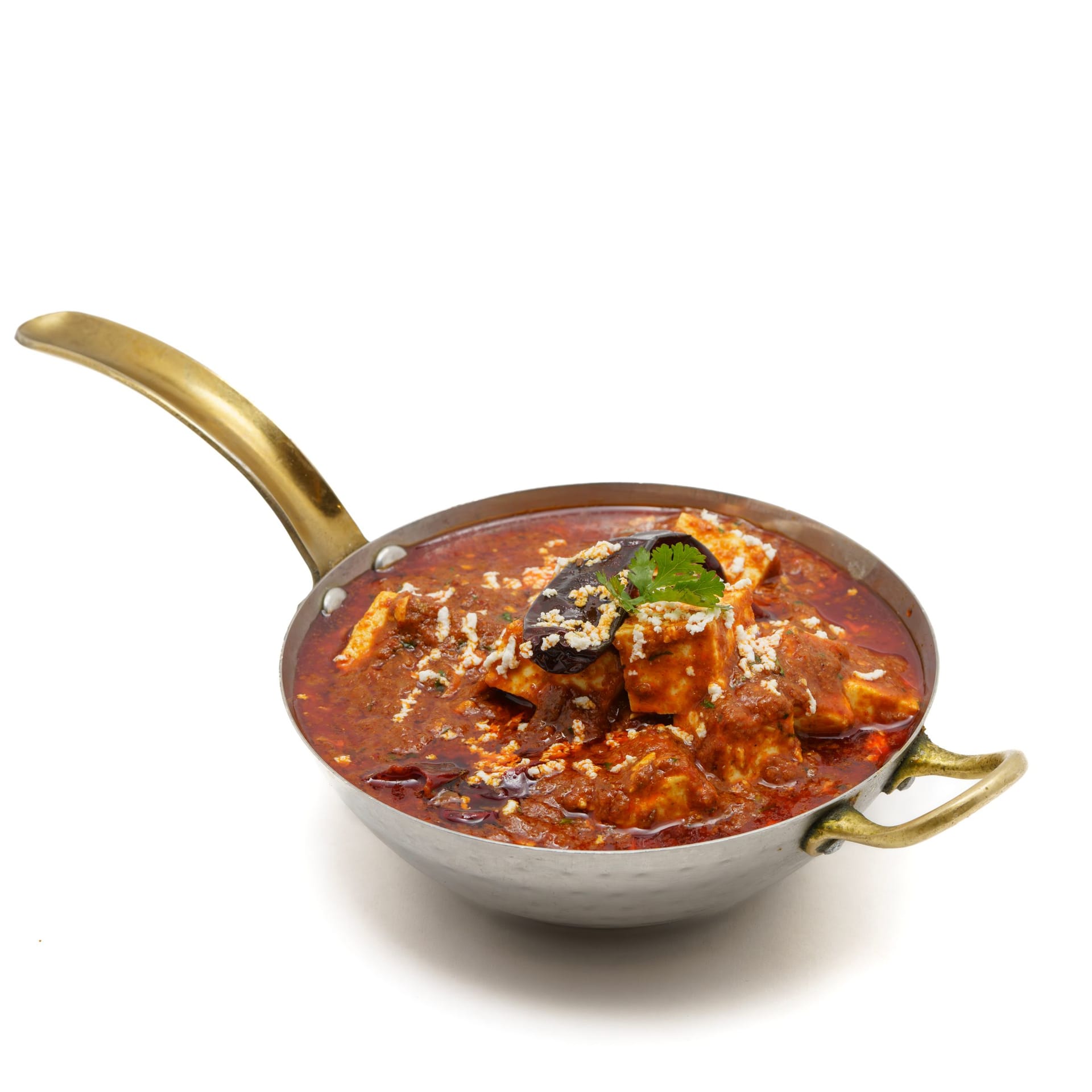 Cubes of paneer in a deep red, oil-slicked masala, served in a steel kadhai with a dried red chilli and grated paneer on top.